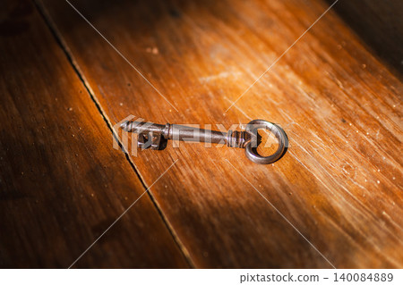 Antique skeleton key resting on weathered wooden surface, vintage metal key illuminated by warm sunlight Antique skeleton key resting on weathered wooden surface, vintage metal key illuminated by warm sunlight 140084889