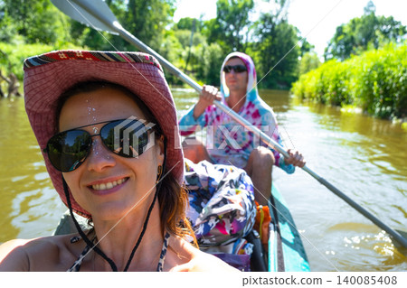 Smiling woman in kayak taking selfie on river, active recreation, adventure gear, water tourism, sport and summer travel. Smiling woman in kayak taking selfie on river, active recreation, adventure gear, water tourism, sport and summer travel. 140085408