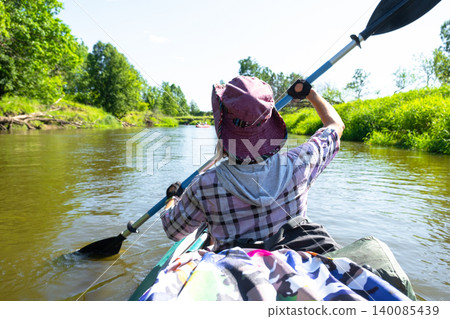 Female kayaker with paddle, enjoying summer river, outdoor sport tourism, adventure recreational experience and gear in use. 140085439