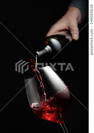 Pouring red wine in a glass goblet. Pouring red wine in a glass goblet. 140085626