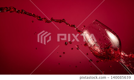 Glass and red wine splash on a red background. Glass and red wine splash on a red background. 140085639