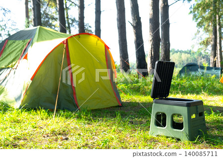Portable camping toilet near yellow tent, outdoor facility, tourism convenience, field use for sanitation and comfort in nature area. Portable camping toilet near yellow tent, outdoor facility, tourism convenience, field use for sanitation and comfort in nature area. 140085711