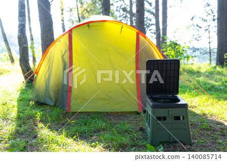 Portable camping toilet by yellow tent in sunlight, travel convenience, field area, tourist hygiene and comfort in wild nature. Portable camping toilet by yellow tent in sunlight, travel convenience, field area, tourist hygiene and comfort in wild nature. 140085714