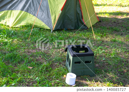 Open portable toilet by tent, outdoor camping facility, convenient hygiene solution for travel, area of use nature tourism application. Open portable toilet by tent, outdoor camping facility, convenient hygiene solution for travel, area of use nature tourism application. 140085727