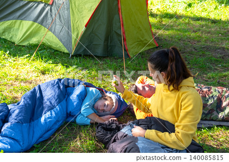 Mom sprays daughter in camping tent, insect repellent, family togetherness, safety for child and adults, active vacation. Mom sprays daughter in camping tent, insect repellent, family togetherness, safety for child and adults, active vacation. 140085815