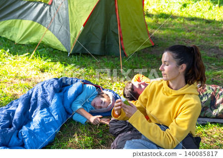 Mother applies mosquito repellent to daughter in tent, outdoor protection for children, healthy active family vacation. Mother applies mosquito repellent to daughter in tent, outdoor protection for children, healthy active family vacation. 140085817