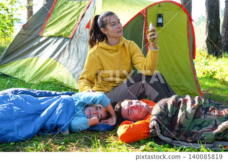Mother at tent with spray bottle, providing insect bite protection for family, safe holidays, outdoors and recreation. Mother at tent with spray bottle, providing insect bite protection for family, safe holidays, outdoors and recreation. 140085819