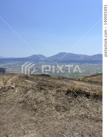 阿蘇火山口寧靜的鄉村景色在下方展開。 阿蘇火山口寧靜的鄉村景色在下方展開。 140085891