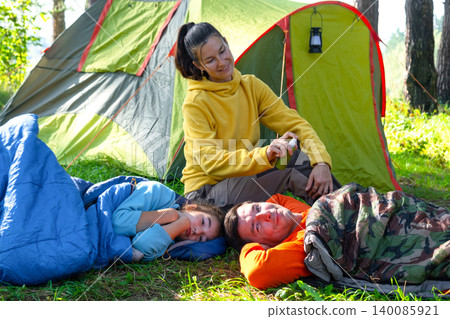 Mother in tent applies bug repellent to children, family health, protection from insect bites, wellness, camping safety, outdoor fun. 140085921