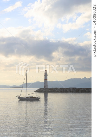 Seascape at sunshine. Lighthouse and sailings on the coast. Seaside town of Turgutreis and spectacular sunshine Seascape at sunshine. Lighthouse and sailings on the coast. Seaside town of Turgutreis and spectacular sunshine 140086328
