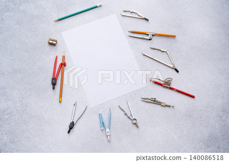 Drawing tools, various draw compasses, supplies around white paper, copy space. Top view of school desk Drawing tools, various draw compasses, supplies around white paper, copy space. Top view of school desk 140086518