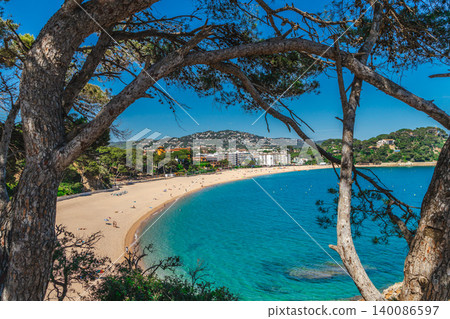 Lloret de Mar beach framed by Mediterranean pine trees on Costa Brava coast Lloret de Mar beach framed by Mediterranean pine trees on Costa Brava coast 140086597