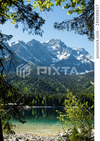 Travel landscape of Eibsee lake and Zugspitze Alps in Bavaria Germany, scenic summer nature panorama with forest and beach, snow mountains peak 140086617