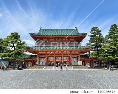 The vibrant vermilion Daigokuden (Great Hall of State) of Heian Jingu Shrine spreads out beneath the blue sky and white clouds. The vibrant vermilion Daigokuden (Great Hall of State) of Heian Jingu Shrine spreads out beneath the blue sky and white clouds. 140086652