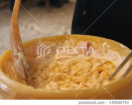 Chef Mixing Creamy Pasta and Ham in Whole Cheese Wheel Chef Mixing Creamy Pasta and Ham in Whole Cheese Wheel 140086743