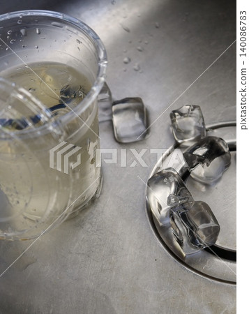Melting Ice Cubes Spilled on Reflective Metal Surface 140086783
