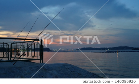 Peaceful Dusk Fishing Scene with Vibrant Sky Over Calm Waters Peaceful Dusk Fishing Scene with Vibrant Sky Over Calm Waters 140086920