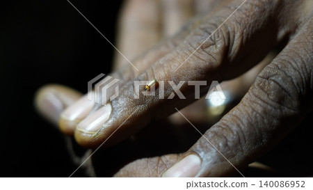 Macro view of a tiny glowing insect on a persons hand Macro view of a tiny glowing insect on a persons hand 140086952