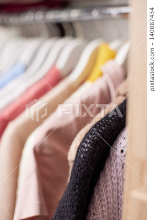 Clothes hanging on a rail inside a modern wooden closet with drawers, showcasing organization and storage Clothes hanging on a rail inside a modern wooden closet with drawers, showcasing organization and storage 140087434