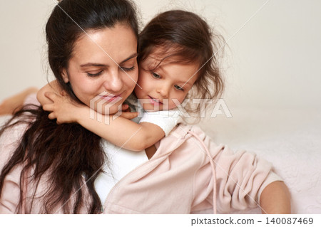 Mother feeling loved as her daughter hugs her from behind, showing strong family connection and tenderness 140087469