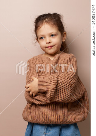 little child girl pouting and looking away with arms crossed, wearing a brown knit sweater little child girl pouting and looking away with arms crossed, wearing a brown knit sweater 140087474