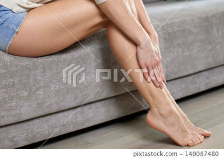 close-up of woman massaging her tired legs and feet, suffering from pain, swelling, and varicose veins 140087480