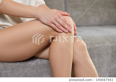 Woman touching her knee, feeling joint discomfort. Concept of knee pain, leg injury, arthritis, and body care 140087481