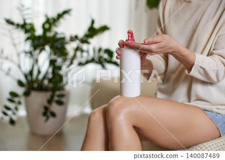 Woman dispensing moisturizing lotion from a pump bottle into her hand, reflecting self-care and beauty ritual Woman dispensing moisturizing lotion from a pump bottle into her hand, reflecting self-care and beauty ritual 140087489