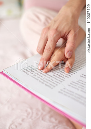 Parent and child hands on an open book, pointing at text, illustrating early childhood education, learning, and bonding Parent and child hands on an open book, pointing at text, illustrating early childhood education, learning, and bonding 140087509