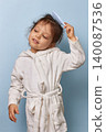 little girl maintaining hygiene and doing her morning routine, standing against a blue background 140087536