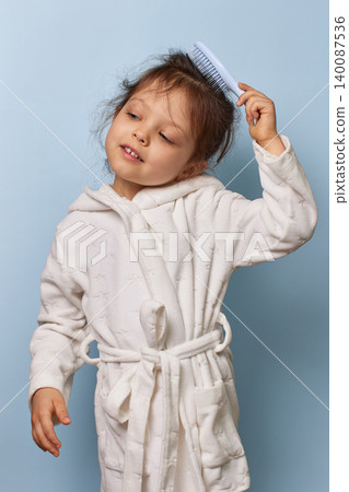 little girl maintaining hygiene and doing her morning routine, standing against a blue background little girl maintaining hygiene and doing her morning routine, standing against a blue background 140087536