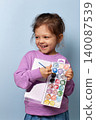 Smiling child girl holding a watercolor palette and brush, ready to paint 140087539