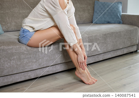 woman massaging her tired legs and feet, suffering from pain, swelling, and varicose veins woman massaging her tired legs and feet, suffering from pain, swelling, and varicose veins 140087541