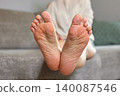 Woman lying on a sofa, relaxing at home, showing the soles of her feet, emphasizing self-care and comfort 140087546
