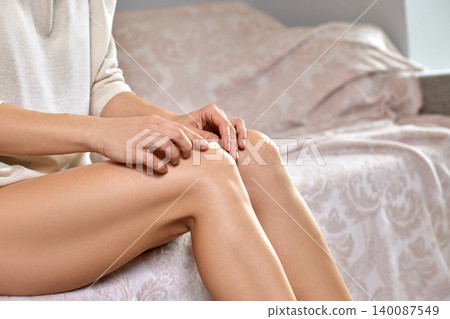 Woman's hands applying a dollop of moisturizing cream onto her bare knee, practicing self-care for smooth, hydrated skin Woman's hands applying a dollop of moisturizing cream onto her bare knee, practicing self-care for smooth, hydrated skin 140087549