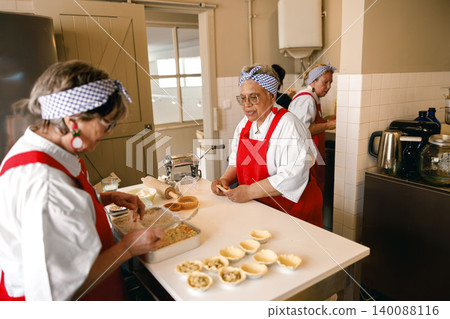 Diverse Senior Women Preparing Homemade Pastries in a Community Kitchen Setting Diverse Senior Women Preparing Homemade Pastries in a Community Kitchen Setting 140088116