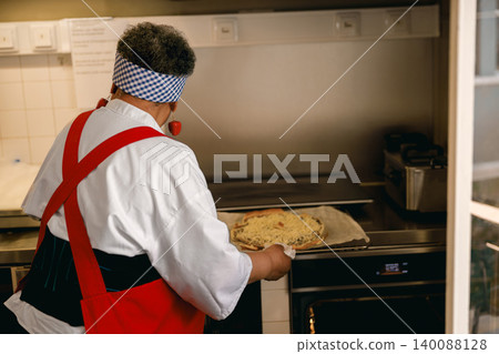 Senior Black Female Cook Preparing Fresh Homemade Pizza in Commercial Kitchen Facility Senior Black Female Cook Preparing Fresh Homemade Pizza in Commercial Kitchen Facility 140088128