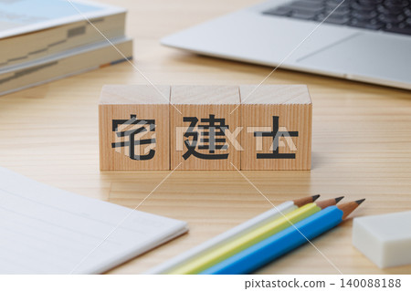 桌子上堆放著一疊積木,上面寫著「房地產經紀人」——象徵著獲得資格認證。 桌子上堆放著一疊積木,上面寫著「房地產經紀人」——象徵著獲得資格認證。 140088188