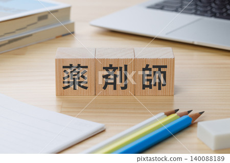 A stack of building blocks on a desk with the word "pharmacist" written on it – an image of obtaining the qualification. A stack of building blocks on a desk with the word "pharmacist" written on it – an image of obtaining the qualification. 140088189