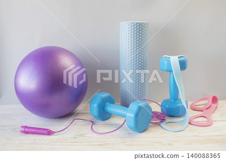 Equipment for yoga and pilates. Yoga blocks, roller, expander and massage ball on a wooden surface. Equipment for yoga and pilates. Yoga blocks, roller, expander and massage ball on a wooden surface. 140088365
