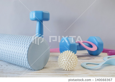 Equipment for yoga and pilates. Yoga blocks, roller, expander and massage ball on a wooden surface. Equipment for yoga and pilates. Yoga blocks, roller, expander and massage ball on a wooden surface. 140088367