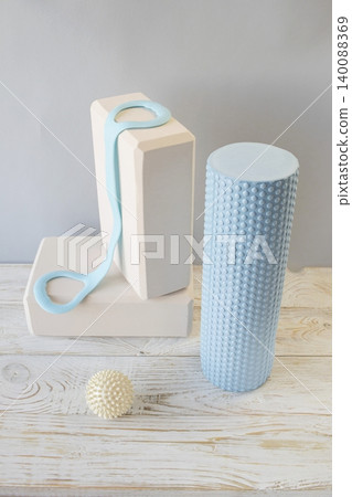 Equipment for yoga and pilates. Yoga blocks, roller, expander and massage ball on a wooden surface. Equipment for yoga and pilates. Yoga blocks, roller, expander and massage ball on a wooden surface. 140088369