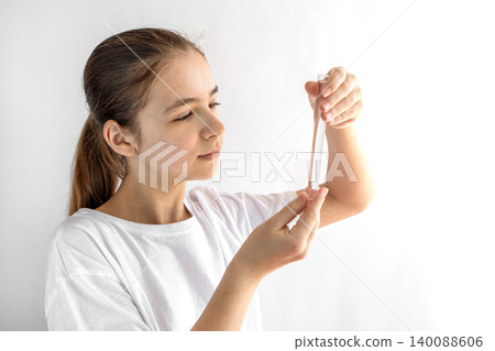Teen girl examining a test tube in a home science experiment with focused expression 140088606