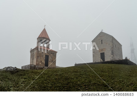 Holy Trinity Church in Gergeti. Misty hill is home to ancient stone chapels. Holy Trinity Church in Gergeti. Misty hill is home to ancient stone chapels. 140088683