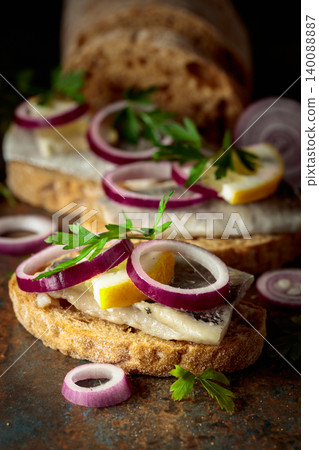 Open sandwiches with herring filet, red onion, lemon, and parsley. Open sandwiches with herring filet, red onion, lemon, and parsley. 140088887