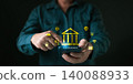 Hands using mobile phone accessing digital banking application with hologram bank building icon. Concept of online financial transaction security and cyber internet payment technology. 140088933