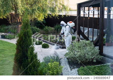 Spring garden pest control: man in protective suit spraying plants Spring garden pest control: man in protective suit spraying plants 140089047