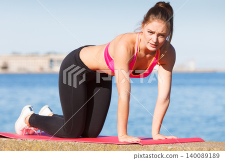 Woman doing sports exercises outdoors by seaside Woman doing sports exercises outdoors by seaside 140089189