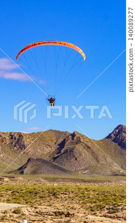 Paraglider soars above hills in clear weather, Spain Paraglider soars above hills in clear weather, Spain 140089277