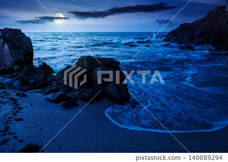 huge stones on the sandy beach at night. mysterious holiday season background at the sea. full moon over clouds on the dark sky above horizon. view of waves washing the shore huge stones on the sandy beach at night. mysterious holiday season background at the sea. full moon over clouds on the dark sky above horizon. view of waves washing the shore 140089294